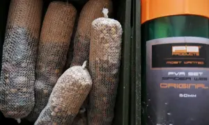 Kilka woreczków z zanętą w siatce PVA, obok zielony pojemnik z pomarańczową nakrętką, na którym widnieje napis "PVA SET SPIDER WEB ORIGINAL".