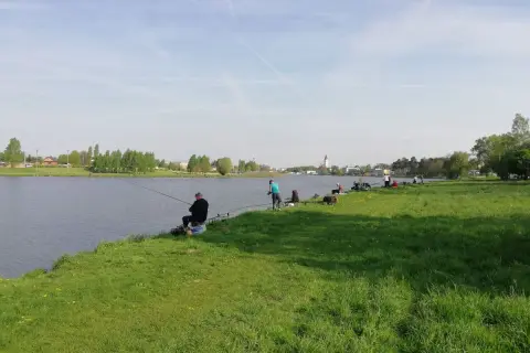Wędkarze relaksują się nad wodą, łowiąc ryby na zalewie Stryków. Słoneczny dzień sprzyja wypoczynkowi.