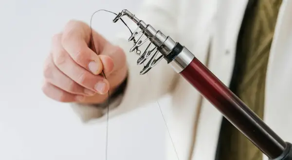 Dłoń trzyma żyłkę przy końcu wędki, przygotowując długość przyponu na leszcza z gruntu.