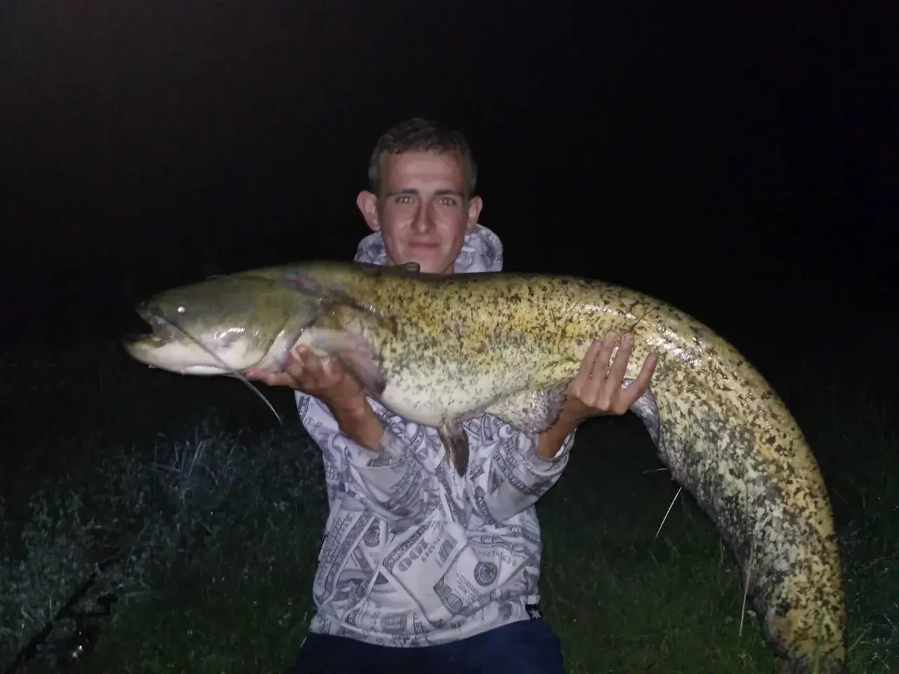 Mężczyzna trzyma ogromnego suma. Czy to jest odpowiedź na pytanie, ile waży sum 100 cm?